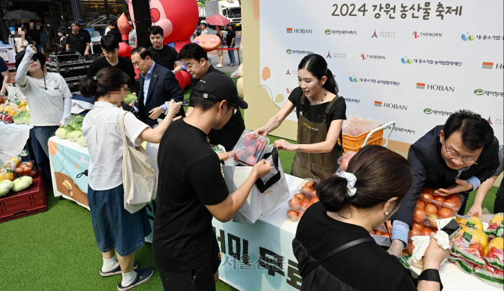 김윤혜 호반프라퍼티 총괄사장과 백종원 더본코리아 대표가 14일 경기 수원시 광교 아비뉴프랑 내 피크닉 파크에서 열린 ‘강원 농산물 소비촉진 행사’에서 참가자들에게 농산물 꾸러미를 나눠주고 있다. 홍윤기 기자