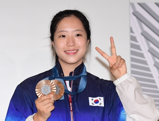 지난 12일 오후 탁구대표팀 선수단과 함께 인천공항 제2터미널을 통해 귀국한 신유빈이 메달 들고 포즈를 취하고 있다. 연합뉴스