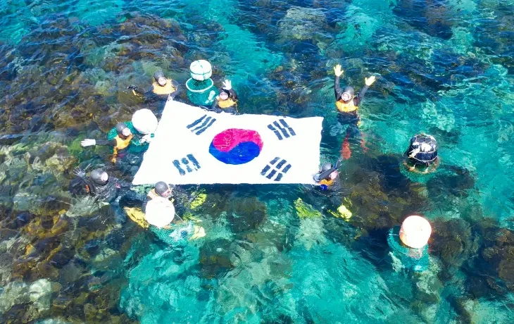 70여년만에 물질시연을 한 제주해녀들이 독도바다에서 태극기를 펼쳐들고 있다. 제주도 제공