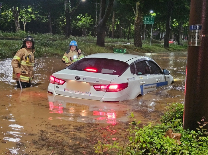 21일 오전 충북 청주시 석소동에서 집중호우로 인해 도로가 침수되어 출동한 소방대원들이 고립된 택시차량을 이동조치하고 있다. 2024.9.21 소방청 제공