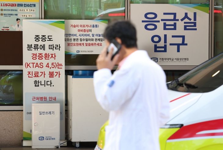 한 의료인이 23일 서울 서초구 한 대형병원 응급의료센터에 놓인 ‘경증 환자 진료 불가’ 안내문 옆을 지나가고 있다. 정부는 새달 상급종합병원 구조 전환 시범사업이 시작되면 응급 의료 위기 해소에도 도움이 될 것으로 내다봤다. 연합뉴스