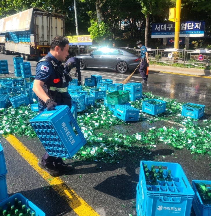 지난 1일 대구 서구 중리네거리에서 25톤 윙바디 화물차에 실린 소주 수백병이 쏟아져 경찰관이 정리하고 있다. 대구경찰청 제공