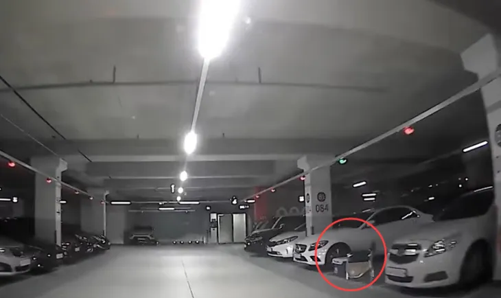한 아파트 지하 주차장이 차량으로 가득 찬 가운데 빈 주차 칸에 자리를 맡기 위한 의자 등 물건(빨간색 원)이 놓여 있다. 유튜브 채널 ‘한문철TV’ 캡처