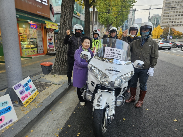 수험생 수송 봉사에 자원한 전국 모터사이클 동호회 ‘모닝캄’ 회원들과 최미숙(왼쪽 두 번째) 학교를 사랑하는 학부모 모임 대표가 입실 시간이 지난 뒤 기념사진을 찍고 있다. 박상연 기자