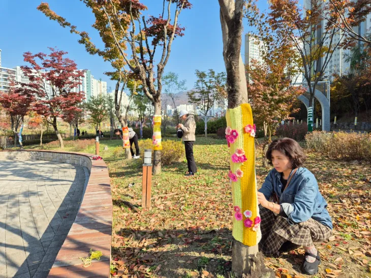 위례뜨개봉사단이 지난 14일 4개월간 만든 뜨개옷을 나무에 입히고 있다. 20~80대 회원 56명으로 구성된 봉사단은 2022년 결성돼 올해로 세 번째 나무에 겨울옷을 입히고 있다.