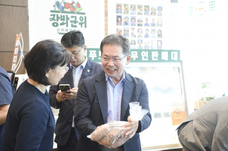 김진열(오른쪽) 군위군수가 27일 군청 현관 로비에서 민원인에게  ‘로컬푸드 무인판매대’에 전시된 친환경 군위 농산품을 소개하고 있다.