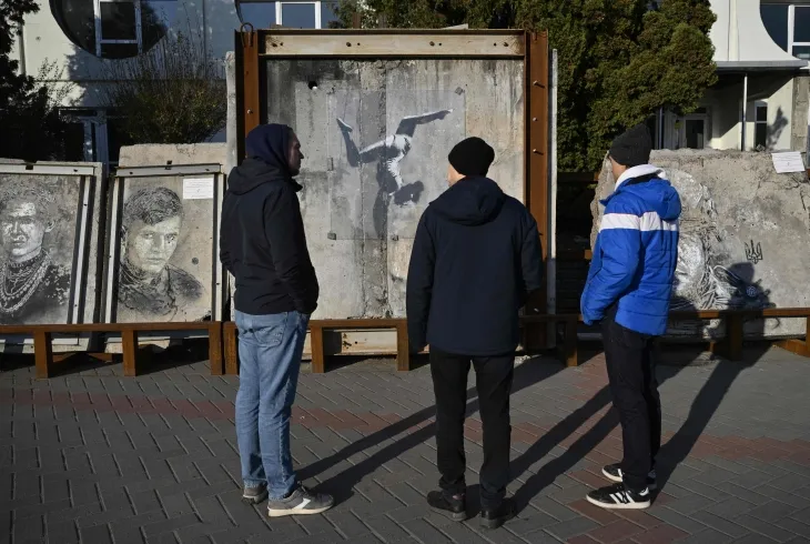 관광객들이 러시아의 우크라이나 침공으로 키이우 보로얀카 지역의 파괴된 건물 유적에 그려진 국제 및 우크라이나 예술가들이 만든 그래피티 야외 전시회를 둘러보며 영국에 거주하는 스트리트 아티스트 뱅크시의 작품을 살펴보고 있다. 2024.11.27 AFP 연합뉴스