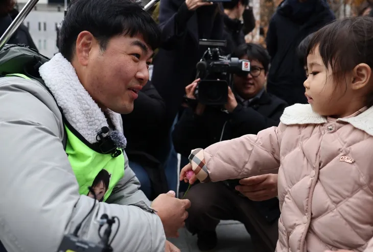 국내에는 치료법이 없는 희귀병을 앓고 있는 네 살 딸 사랑이의 치료비용을 위해 전국 곳곳을 돌며 후원을 요청하고 있는 전요셉 씨가 29일 오후 최종 목적지인 서울 광화문광장에 도착, 마중 나온 사랑이에게 꽃을 받고 있다. 2024.11.29 연합뉴스