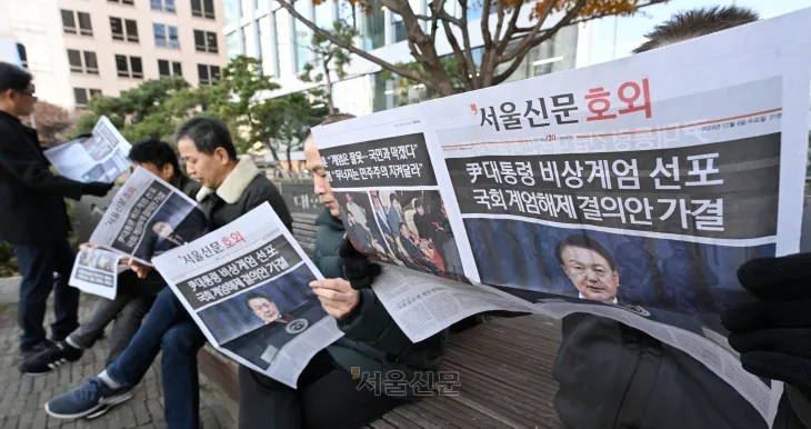 윤석열 대통령이 비상계엄을 선포한 지 6시간여만에 국무회의에서 계엄 해제안이 의결된 가운데 4일 오전 서울 중구 인근에서 시민들이 호외를 읽고 있다. 2024.12.4 홍윤기 기자