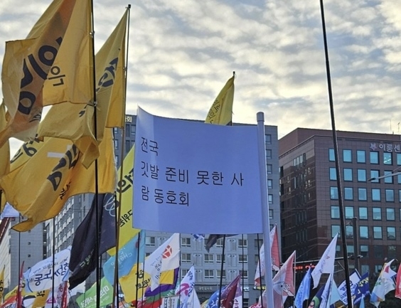 7일 서울 여의도 국회 앞에서 열린 집회에서 한 시민이 ‘전국 깃발 준비 못한 사람 동호회’라는 깃발을 들고 있다. 자료 : 온라인 커뮤니티