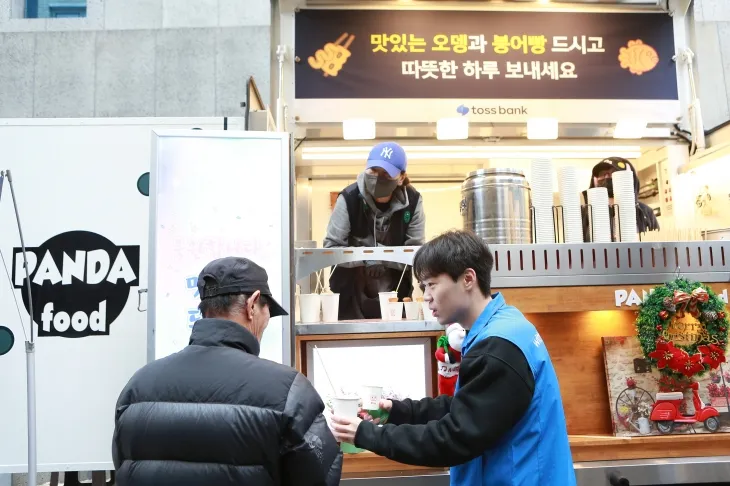 토스뱅크 직원이 20일 서울 돈의동 쪽방촌에서 주민에게 간식을 전달하고 있다.   서울시 제공