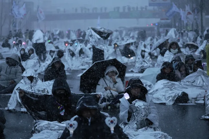 지난 5일 서울 용산구 한남동 대통령 관저 인근에서 열린 윤석열 대통령 체포 촉구 시위에 참여한 사람들이 방한용 은박 비닐을 두른 채 길에 앉아 있다. 2025.01.05 뉴시스