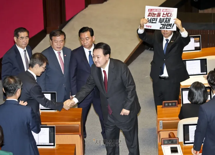 윤석열 대통령이 31일 서울 여의도 국회 본회의장에서 내년도 정부 예산안에 대한 시정연설을 마친 뒤 국무위원들과 인사를 나누고 있다. 윤 대통령 뒤로 진보당 강성희 의원이 예산안 관련 피켓을 들고 있다. 2023.10.31 홍윤기 기자