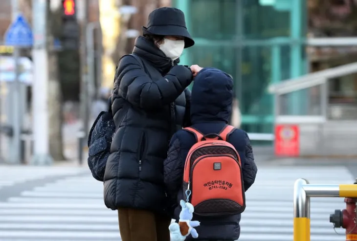 대구 도심 한 횡단보도 앞에서 할머니가 유치원 등원을 앞둔 손주의 외투와 모자를 여며주고 있다. 뉴스1