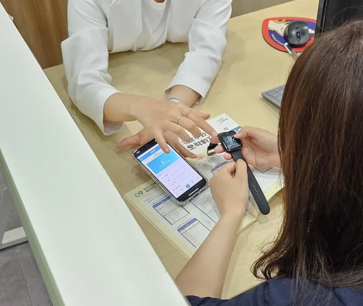 모바일 헬스케어사업 참여 주민이 모바일 앱(채움건강)과 활동량계(스마트밴드)에 대한 설명을 듣고 있다. 구로구 제공