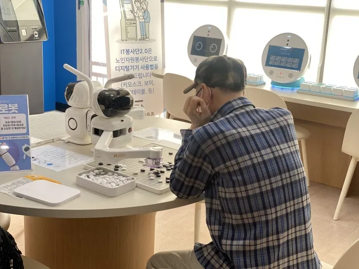 어르신이 AI 바둑 로봇과 대국하며 디지털 기술을 체험하고 있다.