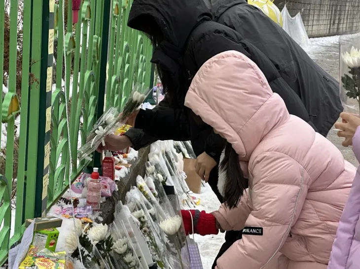 지난달 12일 초등학생 피살 사건이 발생한 대전 서구의 한 초등학교 정문 옆 담장에서 김하늘(7)양을 추모하는 아이와 부모가 꽃을 내려놓고 있다. 대전 뉴시스