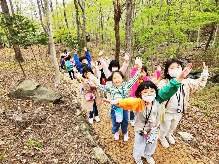 어린이들이 제암산 자연휴양림 안심 어린이 놀이터에서 손을 흔들고 있다.