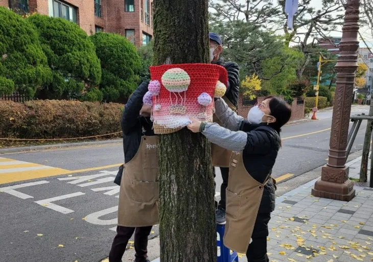서울 희망제작소사업단 참여 주민들이 양말목을 재활용해 만든 옷을 나무에 입히고 있다. 강북구 제공