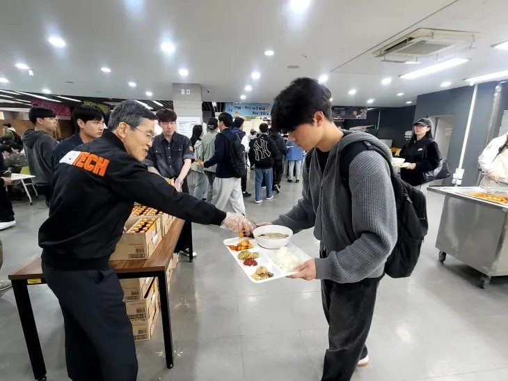 유길상 한국기술교육대 총장이 중간고사 응원 삼계탕 이벤트에서 학생들에게  간식을 나눠주고 있다. 한기대 제공