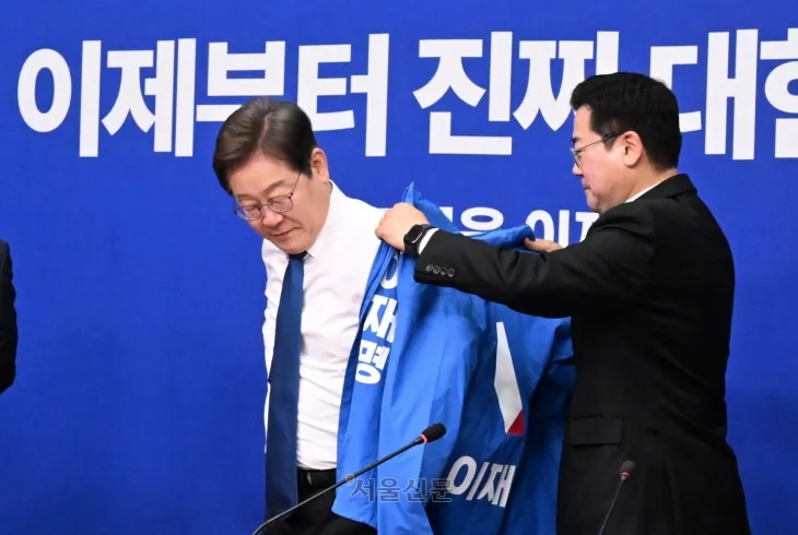 박찬대 더불어민주당 당대표 직무대행 겸 원내대표가 28일 국회에서 열린 당 최고위원회의에서 이재명 대선 후보에게 선거운동용 파란색 점퍼를 입혀주고 있다. 2025.4.28 안주영 전문기자