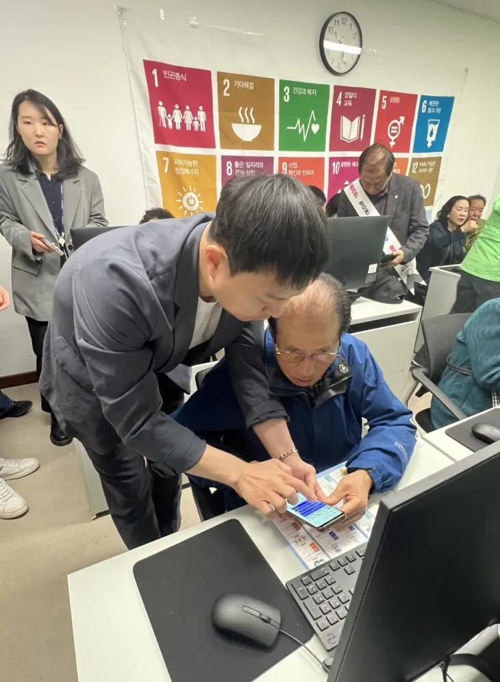 유영일 의원이 어르신에게 기후행동 기회소득 앱 설치 및 사용 방법을 세심하게 안내하고  있다.