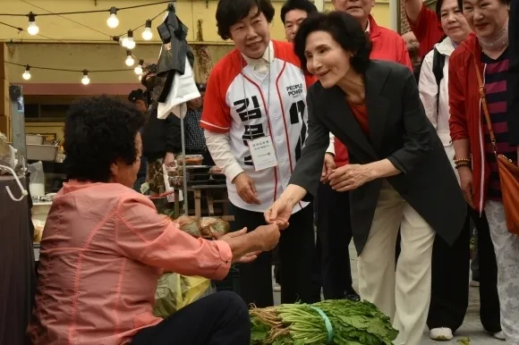 김문수 국민의힘 대선 후보의 배우자인 설난영(오른쪽)씨가 27일 전남 순천의 아랫장을 찾아 상인에게 김 후보의 명함을 건네는 모습. 순천 뉴스1