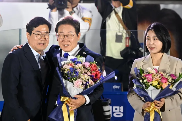 21대 대통령 당선이 확실시되는 이재명 더불어민주당 대선 후보와 부인 김혜경 여사가 4일 서울 여의도 국회 인근에서 당 주최로 열린 국민개표방송 행사에 참석해 박찬대 상임 총괄선대위원장에게 꽃다발을 받고 있다. 2025.6.4 공동취재