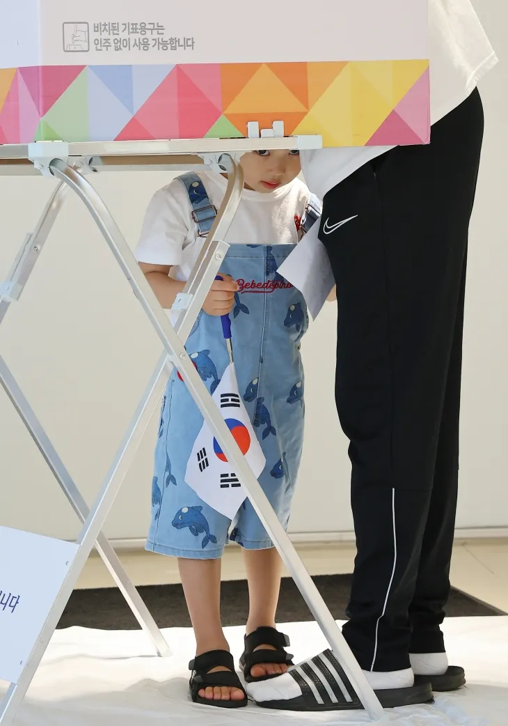 인천 미추홀구 한 자동차 판매 영업소에 마련된 주안5동 제3투표소에서 태극기를 들고 있는 한 어린이가 투표를 하고 있는 보호자를 기다리며 기표소 밖을 살펴보고 있다. 연합뉴스