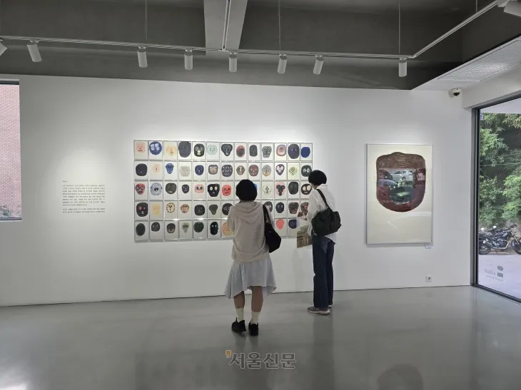 크라우더의 ‘얼굴들’ 연작을 감상하는 관람객의 모습. 이 작품은 그림책의 경계를 넘어 현대 미술로 확장한 크라우더의 예술적 도전을 보여 준다.