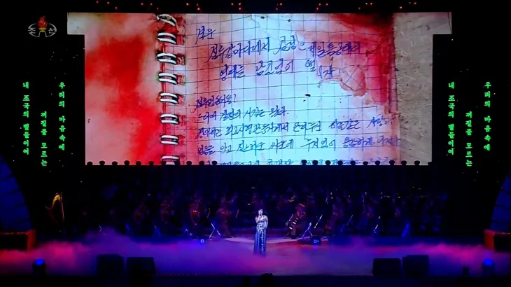 북한이 지난 29일 동평양대극장에서 방북 중인 올가 류비모바 러시아 문화부 장관이 참석한 가운데 열린 예술인 공연 중 무대 배경화면에 피로 얼룩진 수첩에 손글씨로 작성된 러시아 파병 북한군 편지가 상영됐다. 2025.6.30 조선중앙TV 화면 연합뉴스