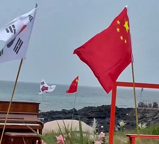 10일 소셜미디어(SNS) 스레드 이용자에 따르면 지난 8일 우도 해안도로변에서 나란히 꽂힌 오성홍기와 태극기가 포착됐다. 2025.7.10 스레드