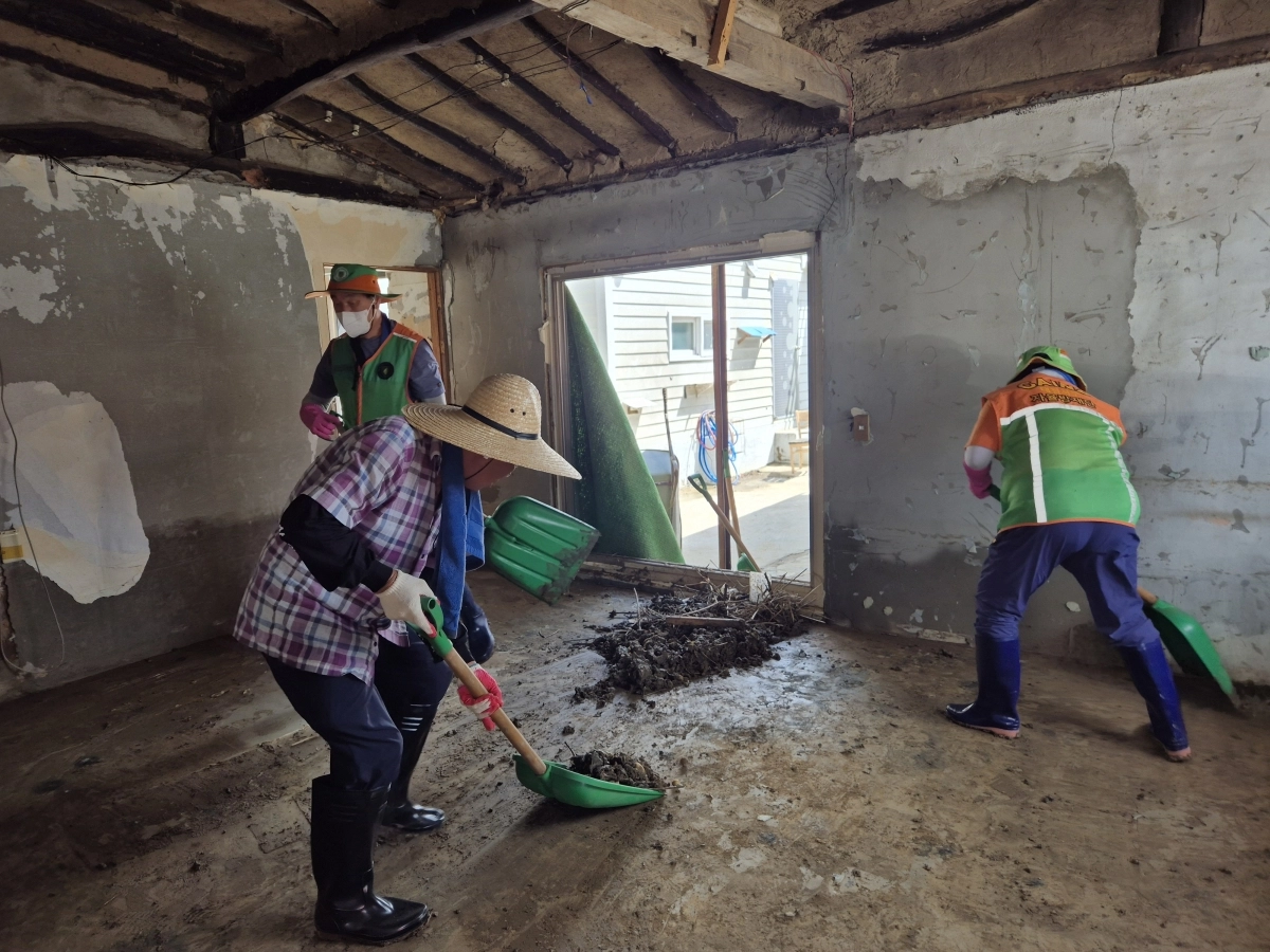 지난 21일 충남 아산시 염치읍 곡교1리 일원에서 자원봉사자들이 밀대로 집안까지 들어찬 진흙을 밀어내고 있다. 김우진 기자