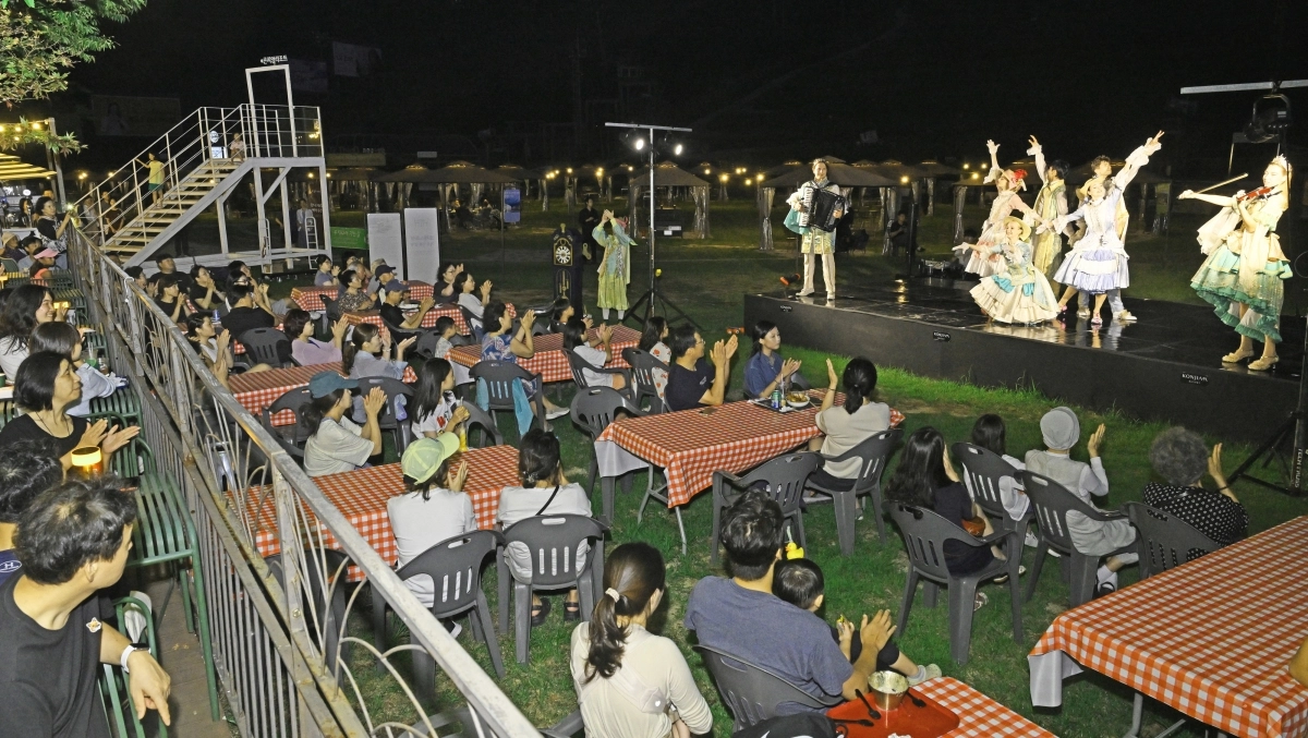 23일 경기도 광주 곤지암리조트 잔지광장을 찾은 투숙객들이 무대 위 배우들이 펼치는 공연을 관람하고 있다. 곤지암리조트는 여름 휴가철을 맞아 7월 11일부터 10월 초까지 ‘한여름 밤의 매직 타임 공연’을 선보인다. 숲 속 요정들의 이야기로 꾸며진 이번 공연은 바이올린·아코디언 연주, 저글링, 거리 공연 등 다양한 콘텐츠로 리조트 전역에서 펼쳐진다.  체크인 공연부터 야외 펍에서의 야간 공연까지, 투숙객 누구나 시간대별로 자유롭게 즐길 수 있도록 구성했으며, 가족 단위 고객에게 동화 같은 추억을 선사할 예정이다. 사진 제공 = 곤지암리조트