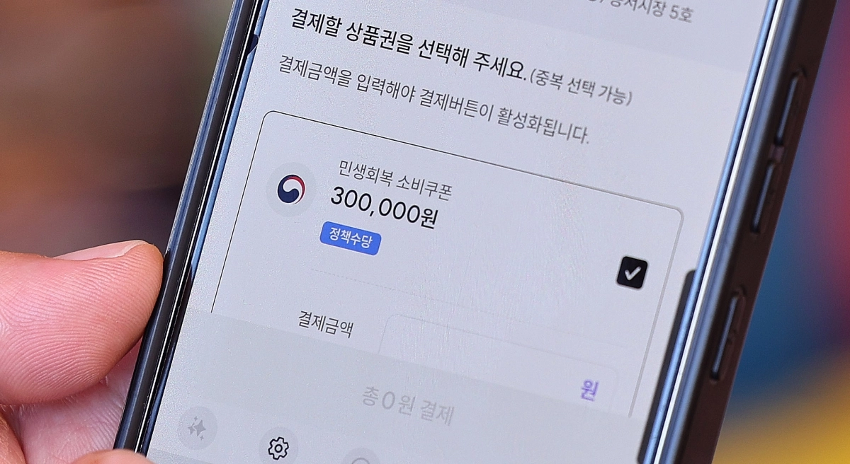 민생회복 소비쿠폰 지급 이후 첫 주말인 지난 27일 서울 동대문구 청량리종합시장을 찾은 한 시민이 민생회복 소비쿠폰을 사용하고 있다. 뉴스1