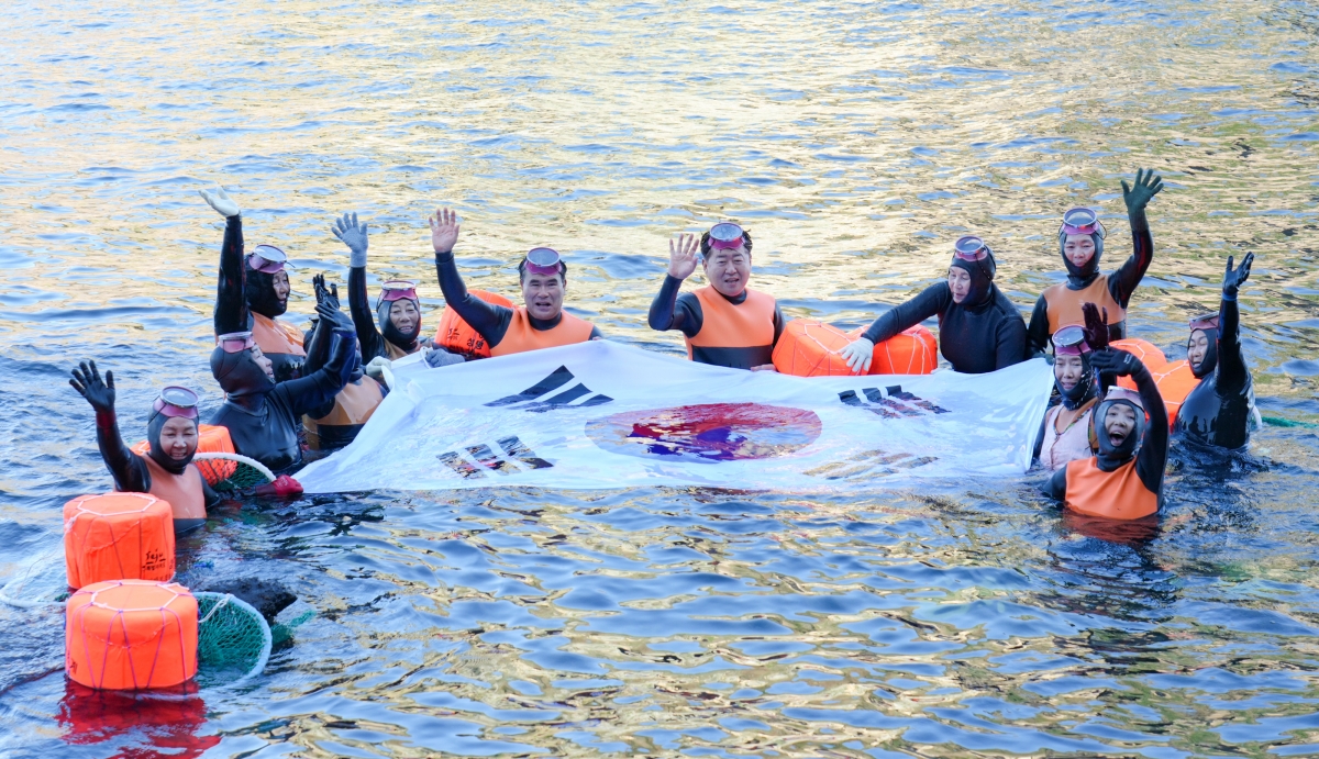 오영훈 제주도지사가 제주·울릉 해녀들과 함께 바다에 들어가 태극기를 펼쳐 보이고 있다. 제주도 제공