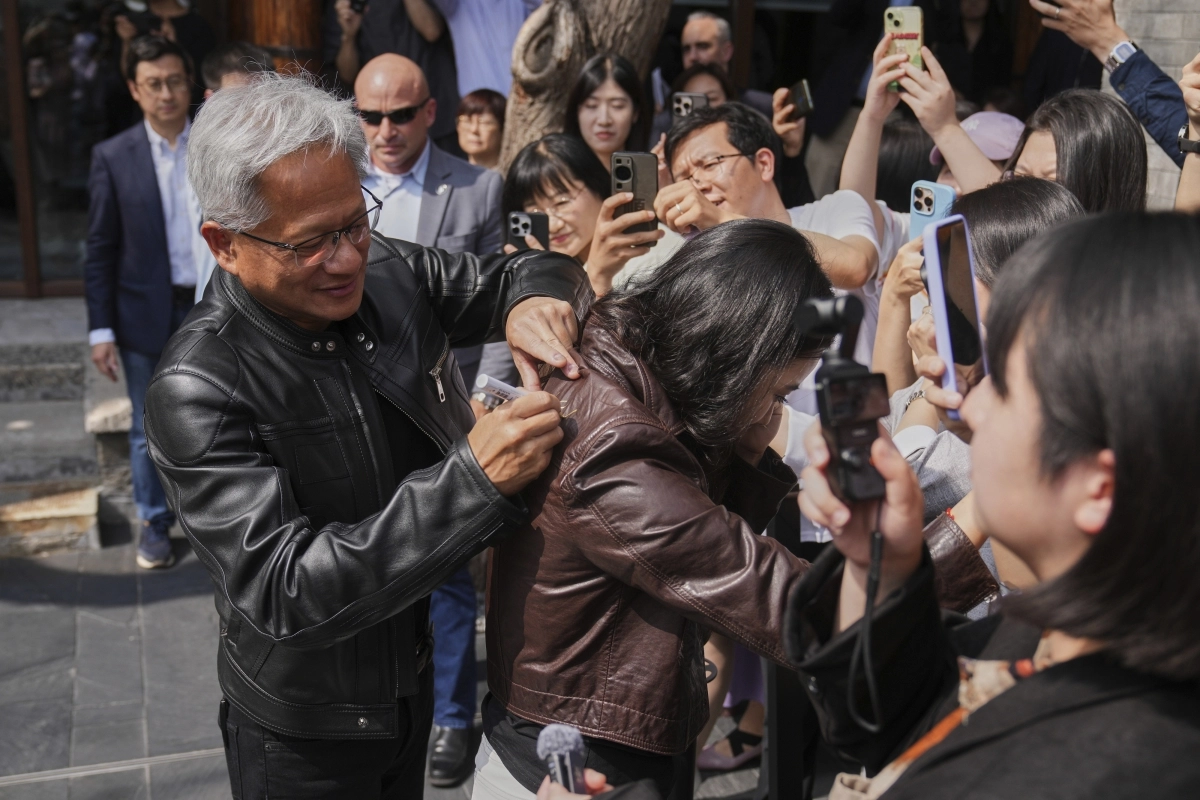 [베이징=AP/뉴시스] 젠슨 황 엔비디아 최고경영자(CEO)가 16일(현지 시간) 중국 베이징에서 열린 제3회 중국 국제 공급망 촉진 박람회(CISCE) 참석 후 만다린 오리엔탈 첸먼 호텔에서 기자회견하면서 한 기자의 가죽 재킷에 사인을 해주고 있다. 2025.07.16.