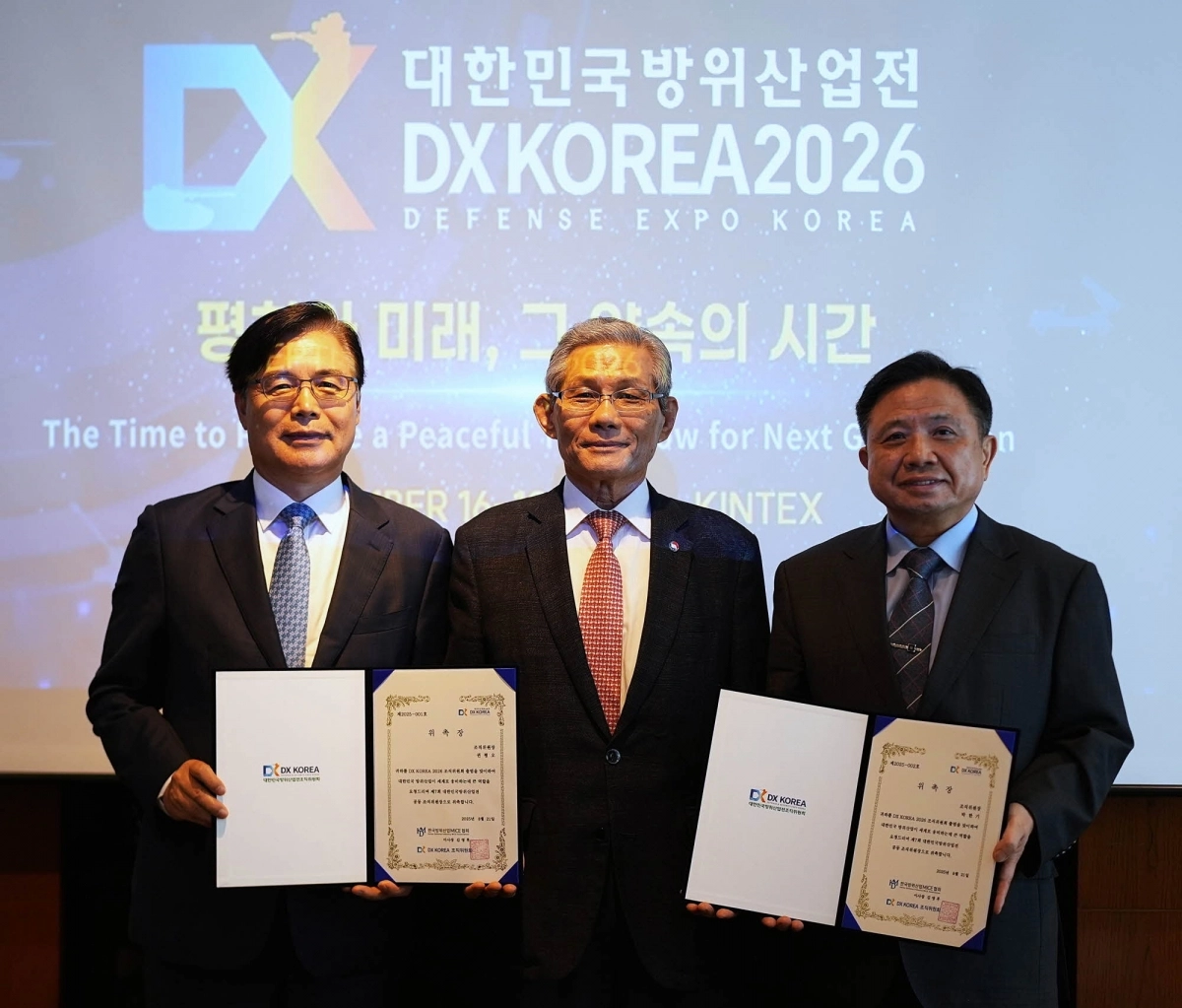 DX KOREA 2026 조직위원회는 서울 삼성동 코엑스(오크우드 호텔)에서 21일 각계 전문가들이 참석한 가운데 (사)한국방위산업MICE협회 김영후 이사장(사진 가운데)이 권평오 전 KOTRA 사장(사진 왼쪽)과 박한기 전 합참의장 (육군대장)에게 공동 조직위원장으로 위촉장을 전달하고 있다. 조직위원회 제공