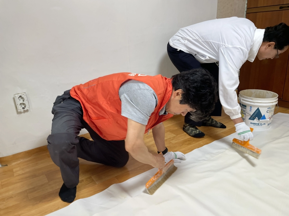 우체국금융개발원(PoSID) 신대섭 원장(사진 왼쪽), 영등포구청 최호권 구청장(사진 오른쪽)이 어르신 가정을 방문해 도배 풀을 칠하고 있다. / 우체국금융개발원 제공