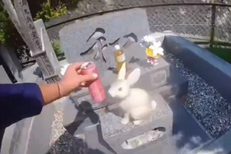 일본을 방문한 호주 관광객이 현지 묘지에 함부로 들어가 제물로 바친 술을 마시는 등 엽기 행각을 벌여 논란이 되고 있다. 사진은 호주 관광객이 일본의 한 묘 앞에 놓인 물건에 손대는 모습. 엑스(X) 캡처