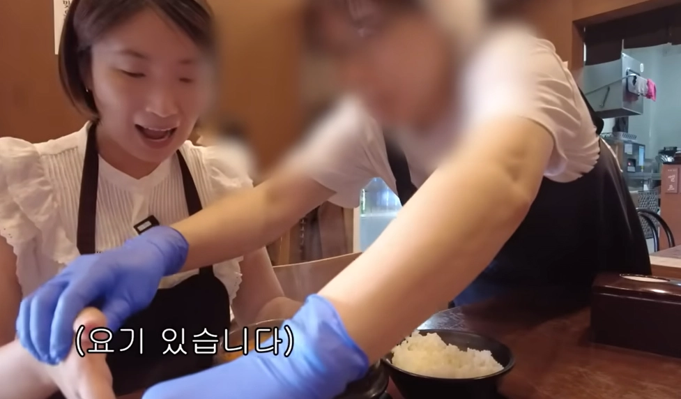 유튜버로 활동 중인 시각장애인 앵커 허우령(왼쪽)가 들어간 강원 동해시 묵호의 한 식당에서 식당 직원이 허씨에게 그릇이 어디 있는지 손으로 알려주고 있다. 유튜브 채널 ‘우령의 유디오’ 캡처