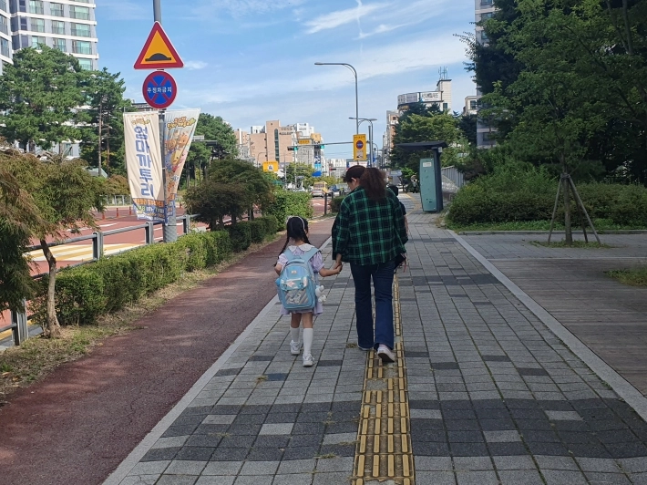 수원 새빛돌보미가 초등학교 저학년 학생의 손을 잡고 학교에서 학원으로 동행돌봄 중인 사진. (수원시 제공)