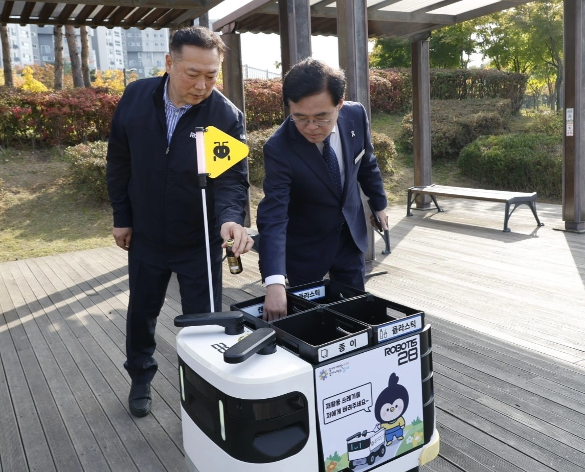진교훈(오른쪽) 서울 강서구청장이 지난달 29일 마곡하늬공원에서 실증 중인 인공지능(AI) 기반 자율주행 로봇을 호출해 병을 버리고 있다. 강서구 제공