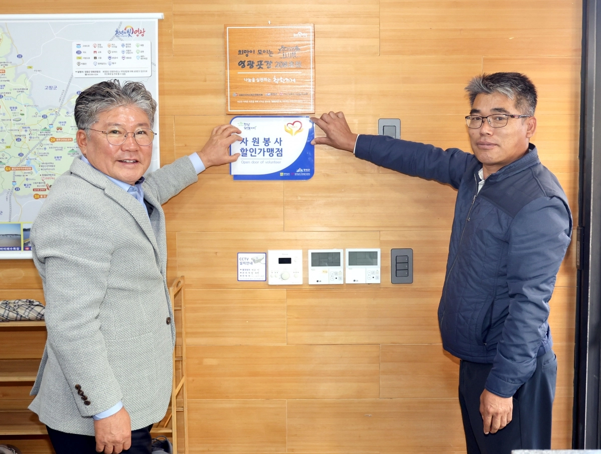 장세일 전남 영광군수가 우수자원봉사자에게 혜택을 주는 마일리지제 가맹점에 현판을 달아주고 있다. (영광군 제공)