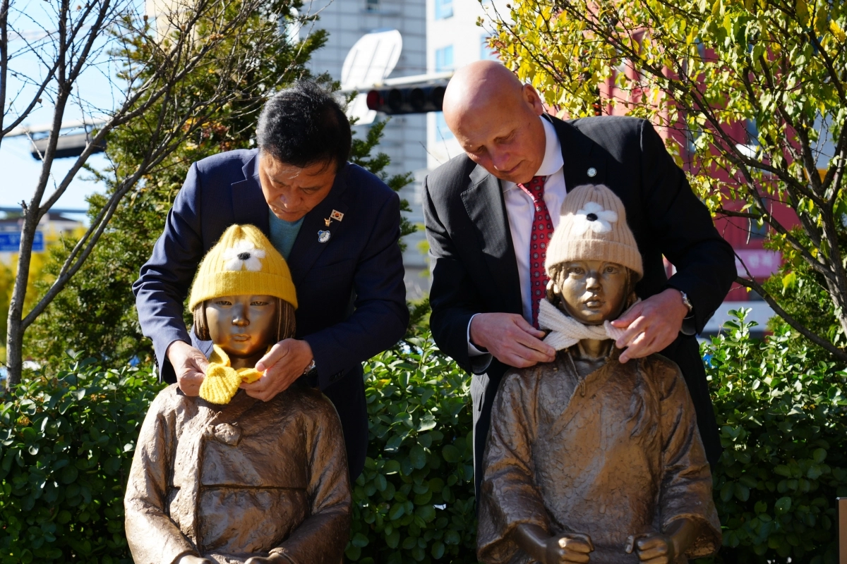 이승로(왼쪽) 서울 성북구청장과 아라 나자리안 미국 글렌데일시장이 지난 10일 성북천 분수마루 광장에 있는 ‘평화의 소녀상’에﻿게 털모자와 목도리를 직접 둘러 주고 있다. 성북구 제공