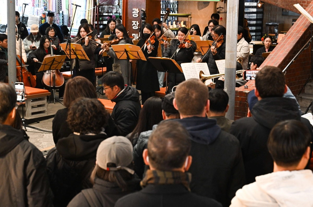 18일 서울 종로구 광장시장에서 열린 ‘2025 서울바이브’에서  지나가던 관광객들이 공연을 보고 있다.