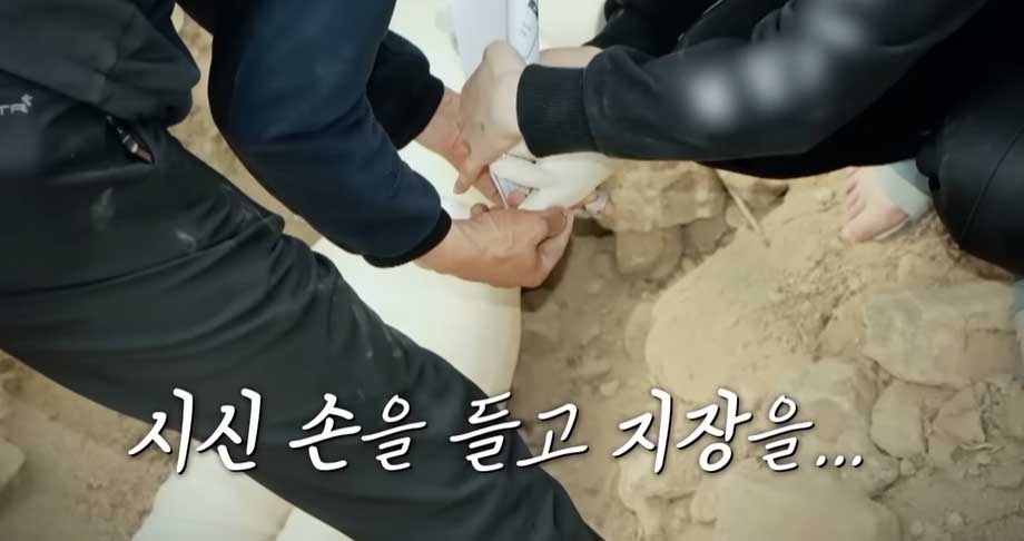 이 씨가 A씨가 암매장된 곳에서 시신을 꺼내 가짜 계약서에 지장을 찍는 모습을 현장검증에서 재연하고 있는 장면    사진-E채널 용감한 형사들 캡처