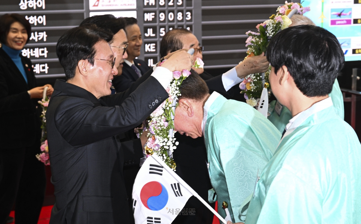 김민석 국무총리와 우원식 국회의장이  23일 서울 강서구 김포국제공항 국제선 입국장에서 열린 ‘대한민국임시정부 요인 환국 재현’ 행사에서 임시정부 요인 후손들에게 꽃 목걸이를 걸고 있다. 2025.11.23 이지훈 기자
