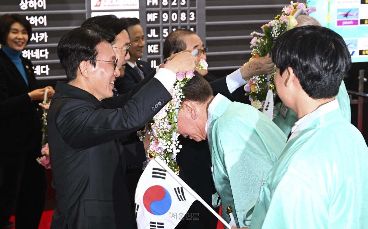 김민석 국무총리와 우원식 국회의장이  23일 서울 강서구 김포국제공항 국제선 입국장에서 열린 ‘대한민국임시정부 요인 환국 재현’ 행사에서 임시정부 요인 후손들에게 꽃 목걸이를 걸고 있다. 2025.11.23 이지훈 기자