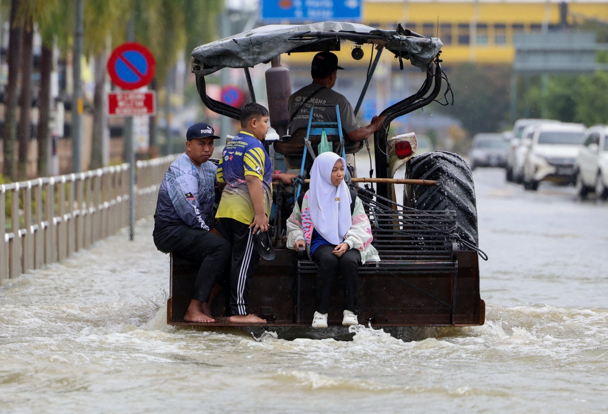 말레이시아 캉가르에서 태국과 국경을 접하고 있는 말레이시아 북부 주에서 폭우가 내린 후 사람들이 트랙터를 타고 홍수 지역을 건너고 있다. 2025.11.26 로이터 연합뉴스